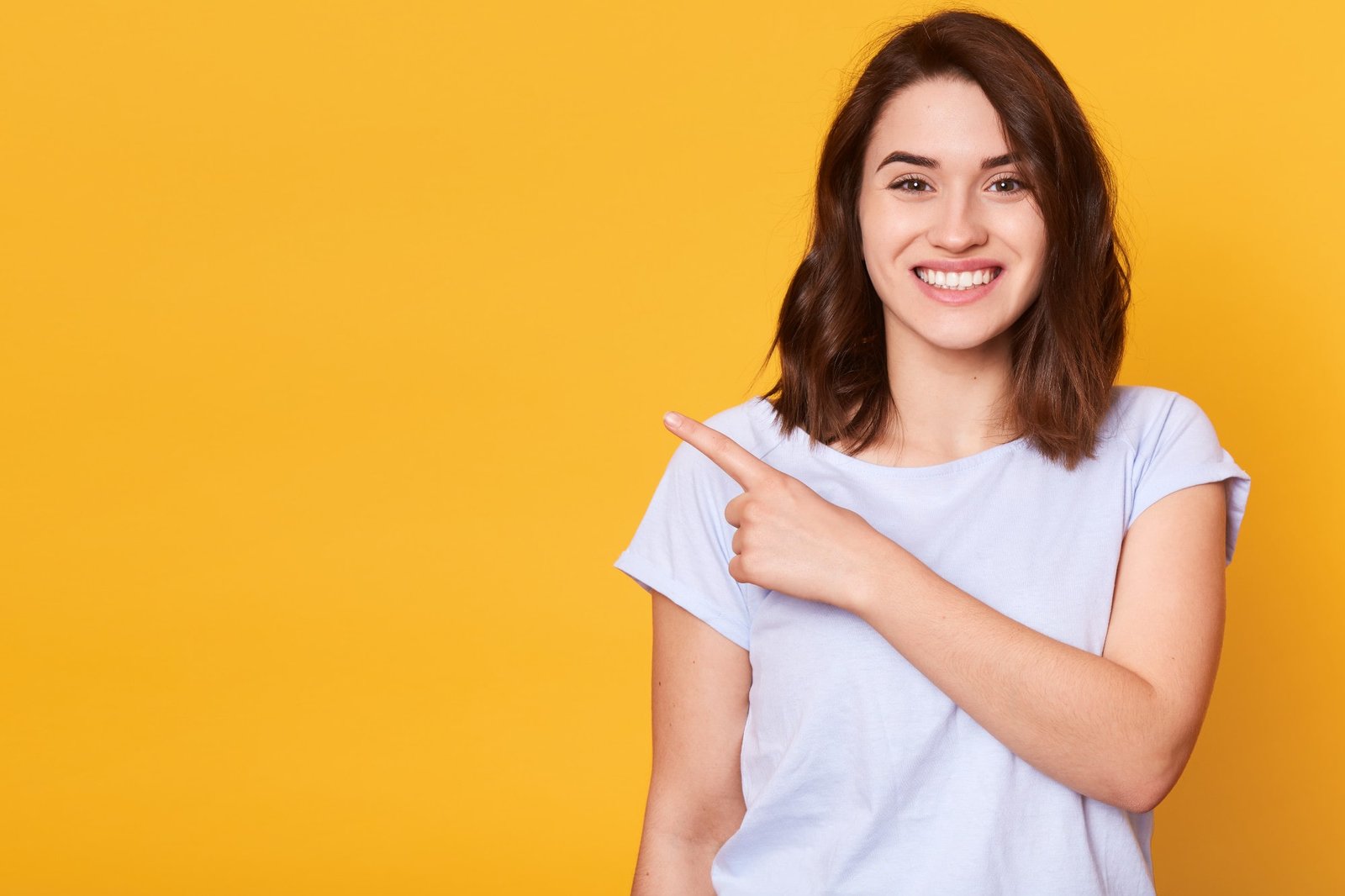 close-up-portrait-nice-cute-adorable-smiling-charming-cheerful-girl-pointing-with-her-index-finger-min