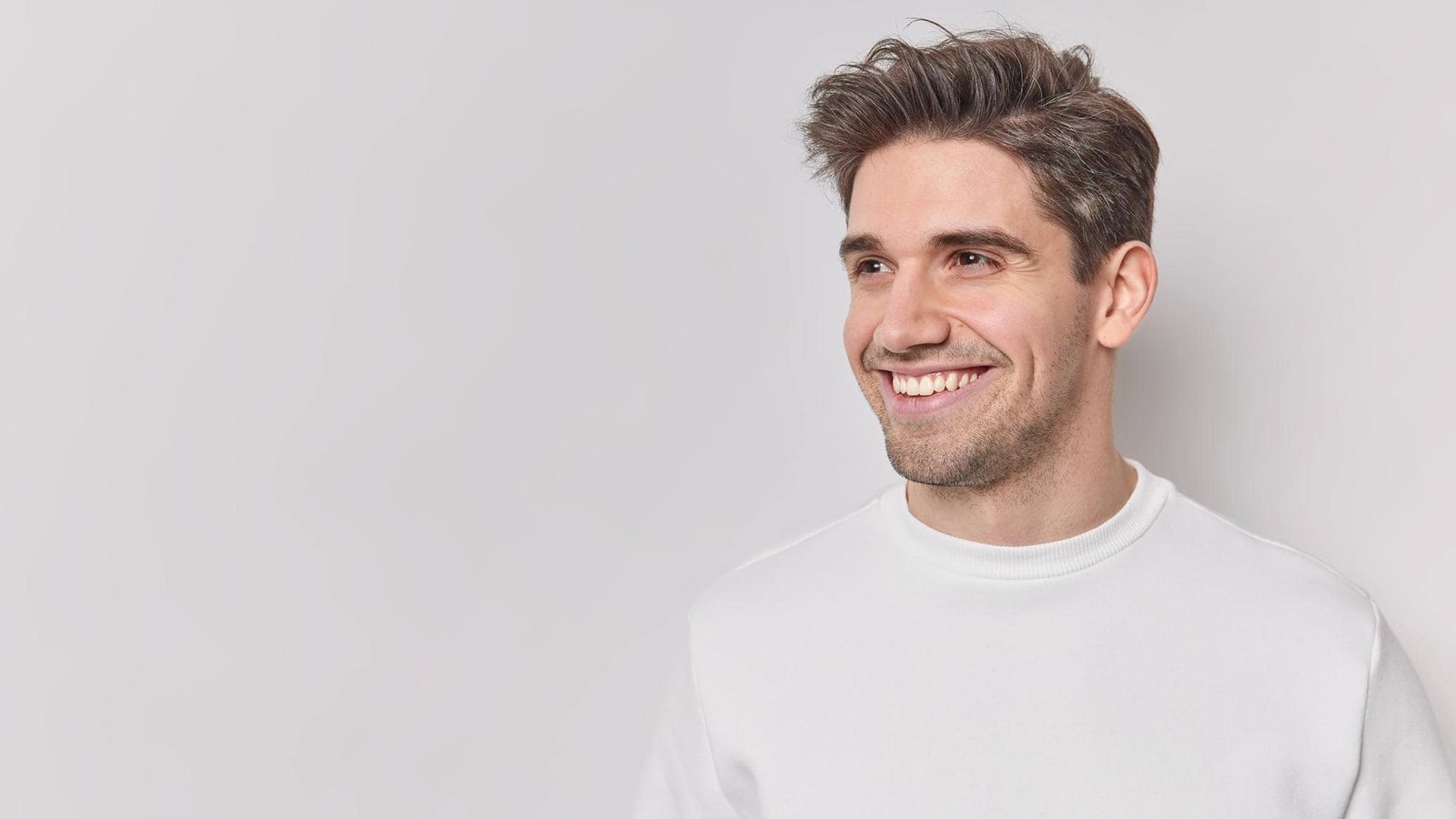 horizontal-shot-handsome-pleased-european-man-looks-away-with-happy-smile-face-dressed-casually-feels-satisfied-notices-something-into-distance-isolated-white-bacground-blank-copy-space-min